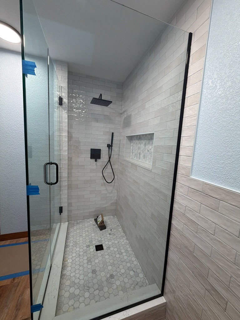 White subway tile shower remodel with niche and black shower fixtures