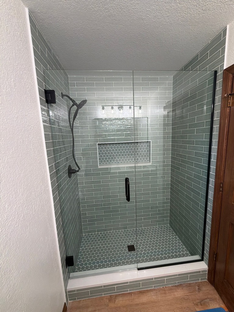 Tile shower remodel with green subway tile and glass enclosure
